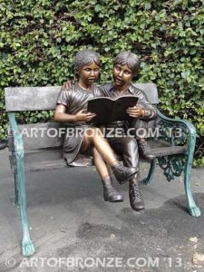 Friendship bronze sculpture of young girl and boy sitting on bench looking at book