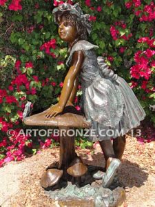 Wonderland bronze sculpture of giant mushroom and standing girl with frog