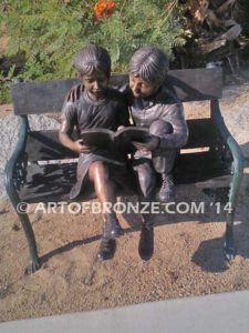 Friendship bronze sculpture of young girl and boy sitting on bench looking at book