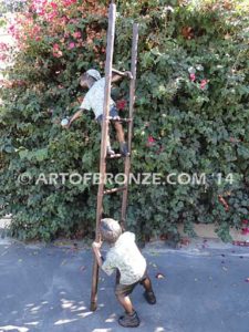 Picking Apples bronze sculpture of young boy holding up ladder for his brother climbing up