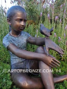 Garden Surprise bronze sculpture of girl sitting with crossed legs and bird on her hand