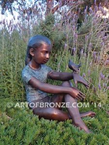 Garden Surprise bronze sculpture of girl sitting with crossed legs and bird on her hand