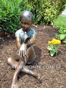 Garden Surprise bronze sculpture of girl sitting with crossed legs and bird on her hand