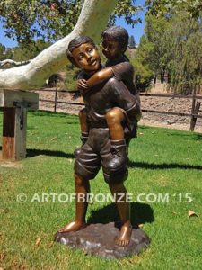 Piggyback bronze statue of boy carrying young girl on his back