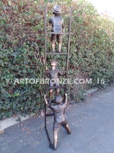 Team Work bronze sculpture of two boys climbing ladder working on house