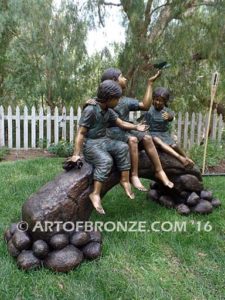 Butterfly Enchantment bronze statue of three children sitting on log playing with butterflies