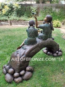 Butterfly Enchantment bronze statue of three children sitting on log playing with butterflies