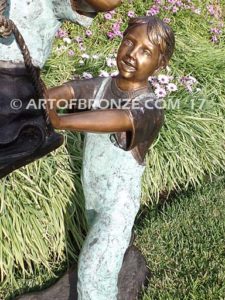 Push Me Higher bronze sculpture for park or playground of boy pushing girl on swing