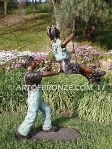 Push Me Higher bronze sculpture for park or playground of boy pushing girl on swing