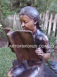 Little learner sculpture of sitting girl reading book on bench