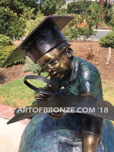 Global Scholar bronze sculpture of boy sitting on globe wearing graduation cap and reading book