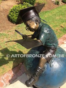 Global Scholar bronze sculpture of boy sitting on globe wearing graduation cap and reading book