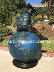 Global Scholar bronze sculpture of boy sitting on globe wearing graduation cap and reading book