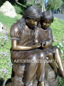 Blessing Hands garden statue of two girls sitting on rock base holding a bird