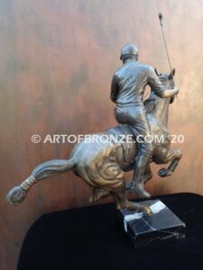 Downfield sculpture of polo player riding his leaping polo pony attached to a marble base