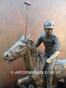 Downfield sculpture of polo player riding his leaping polo pony attached to a marble base