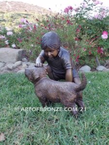 Scrappy bronze garden sculpture of boy playing with his dog