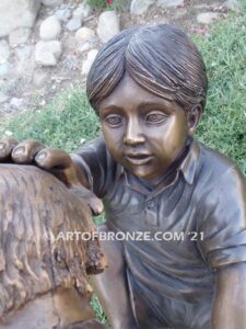 Scrappy bronze garden sculpture of boy playing with his dog