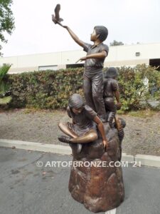 High Hopes bronze sculpture of four children playing on bronze rock for park or school playground