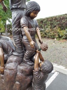 High Hopes bronze sculpture of four children playing on bronze rock for park or school playground