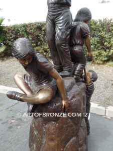 High Hopes bronze sculpture of four children playing on bronze rock for park or school playground