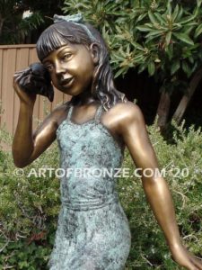 Captivating bronze fountain statue of girl standing listening to seashell