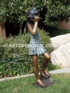 Captivating bronze fountain statue of girl standing listening to seashell