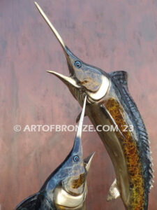 Parlay bronze sculpture of two marlins leaping upward above ocean waves on marble base
