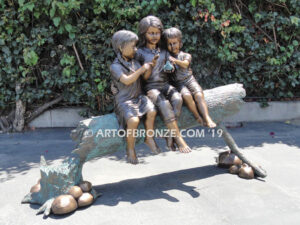 Special Touch bronze sculpture of three kids sitting on log with a injured baby bird in their hands