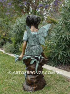 Flower Fairy bronze statue of graceful fairy sitting on rock holding foxglove