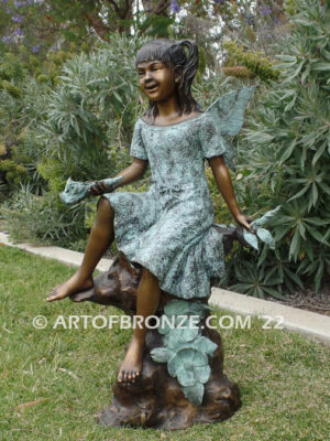 Flower Fairy bronze statue of graceful fairy sitting on rock holding foxglove