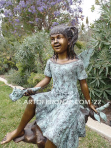 Flower Fairy bronze statue of graceful fairy sitting on rock holding foxglove