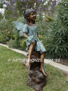 Flower Fairy bronze statue of graceful fairy sitting on rock holding foxglove