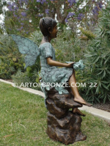 Flower Fairy bronze statue of graceful fairy sitting on rock holding foxglove