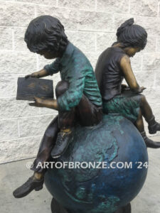 Global Scholars bronze sculpture of boy and girl sitting on globe reading book