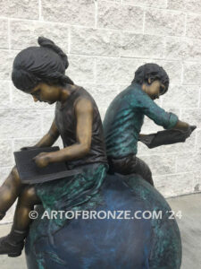 Global Scholars bronze sculpture of boy and girl sitting on globe reading book