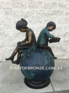 Global Scholars bronze sculpture of boy and girl sitting on globe reading book