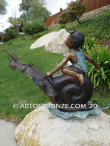 Snail Race outdoor bronze statue of young boy on snail