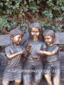 Special Touch bronze sculpture of three kids sitting on log with a injured baby bird in their hands