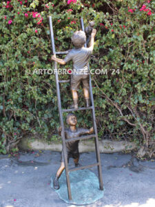 Team work bronze statue children climbing ladder to rescue cat for outdoor display