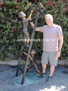 Team work bronze statue children climbing ladder to rescue cat for outdoor display