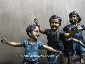 Log of Happiness bronze sculpture of four kids and dog playing on log